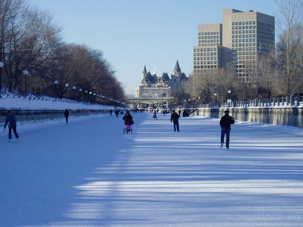 Daytime shot of people skating on the Rideau Canal in Ottawa. Chateau Laurier visible in background
