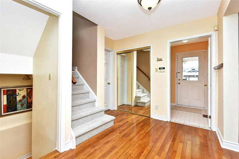 Entry way of a home showing the front door, stairs going up and down as well as a mirrored closet.